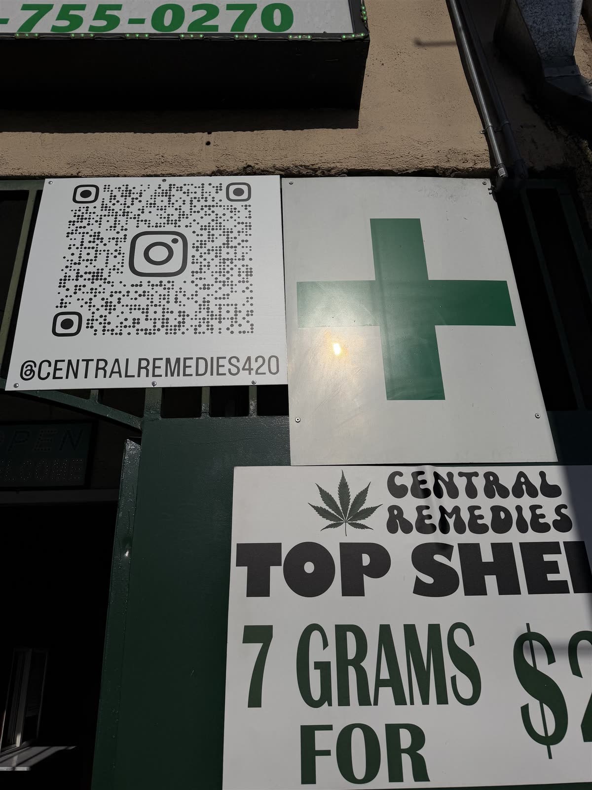 Signs at the entrance of Central Remedies — a green cross, an Instagram QR code for @centralremedies420, and a Central Remedies top-shelf board.